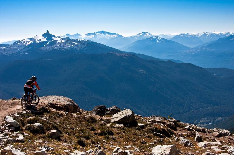 Person riding a bike on top of a cliff overlooking mountains. 